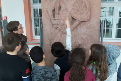 Gruppe von Kindern, die vor einem Steinrelief steht