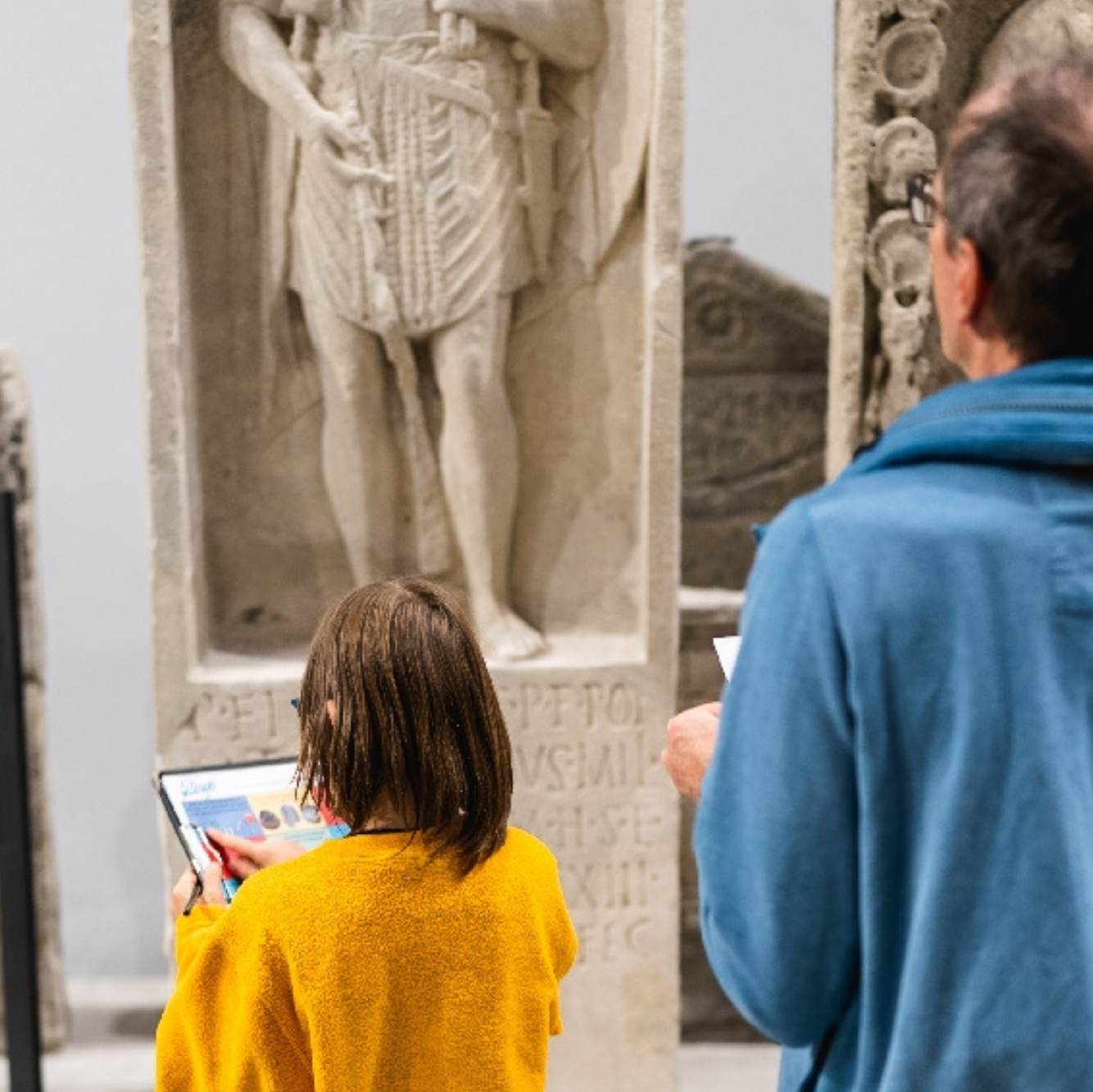 Kind und Erwachsener, die sich Steinfiguren im Museum angucken